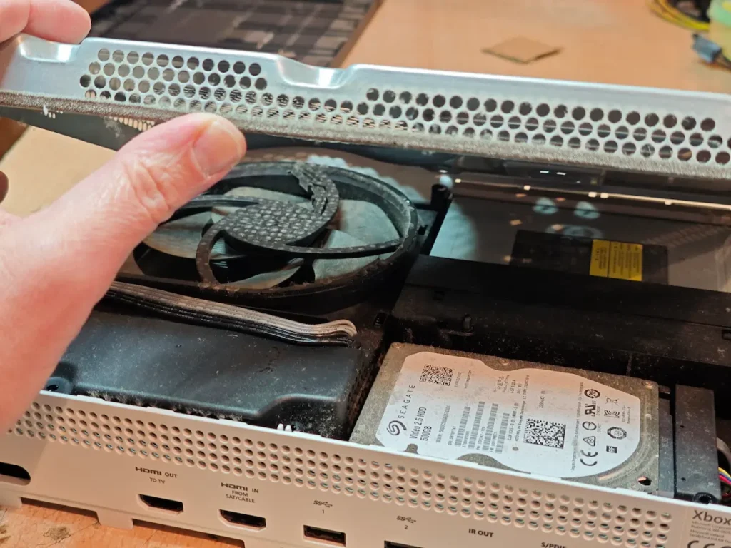 Podizanje metalnog poklopca i prikaz nakupljene prašine unutar Xbox-a