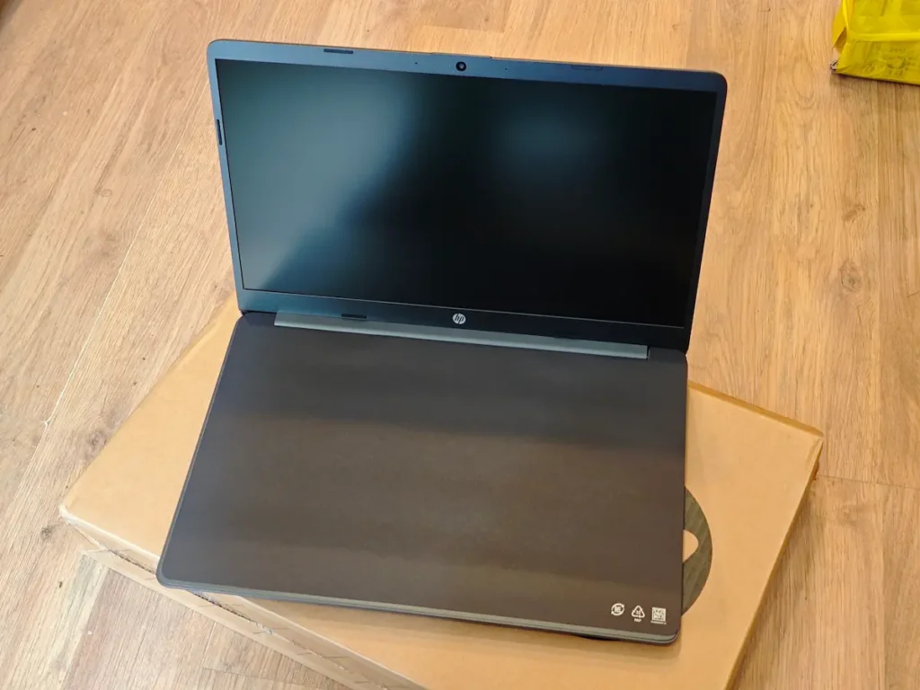Potpuno nov HP laptop poluotvoren na originalnoj kartonskoj ambalaži sa zaštitnim papirom preko tastature pre prve upotrebe