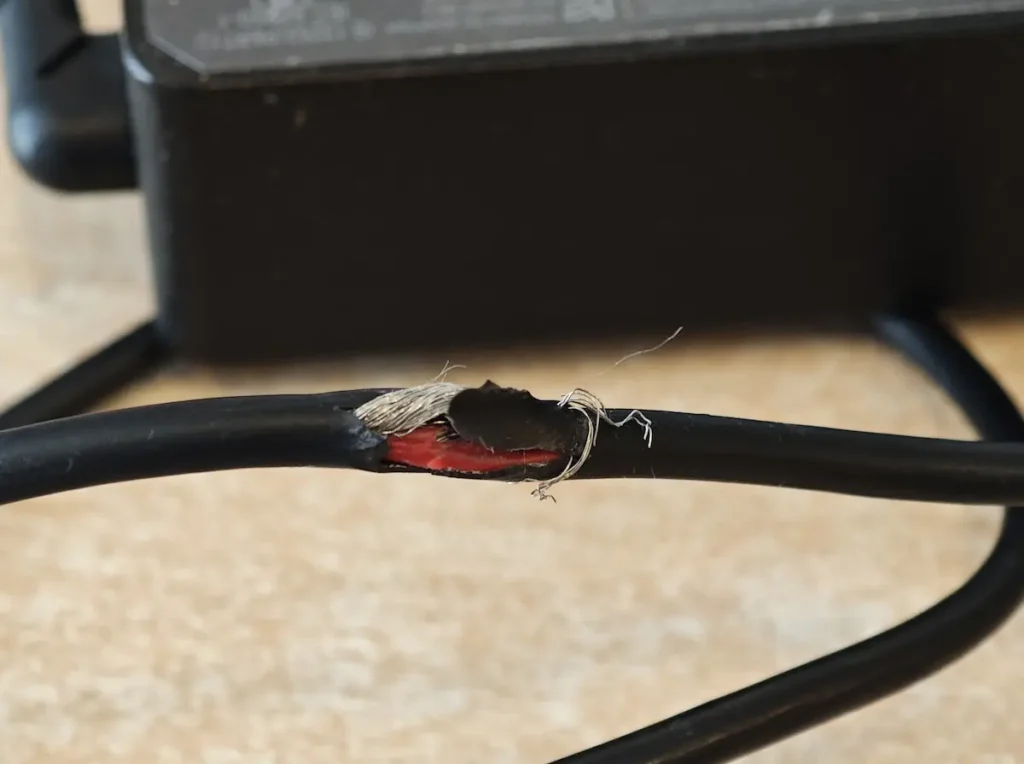 Oštećen kabl punjača za laptop sa vidljivim žicama