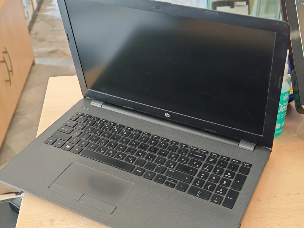 Otvoren polovan laptop gde se jasno vidi izlizan i uglačan tačped od intenzivnog svakodnevnog korišćenja