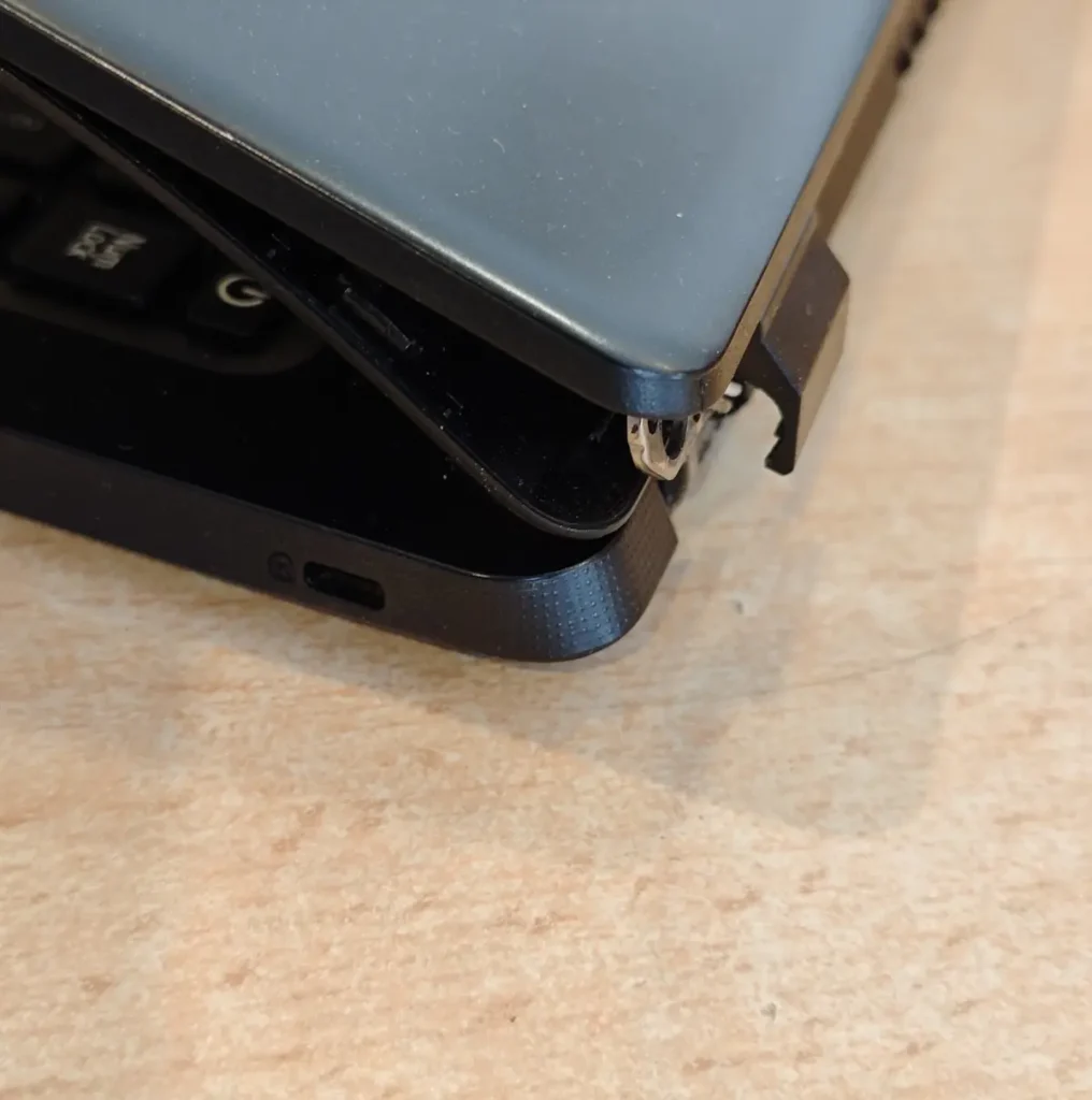 Otvoren polovan laptop sa puknutom plastikom i oštećenom šarkom ekrana usled nepažljivog otvaranja