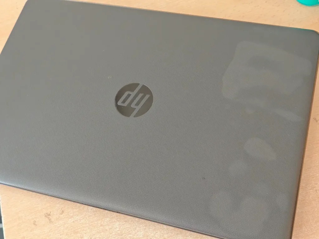 Poklopac polovnog HP laptopa sa vidljivim flekama i tragovima korišćenja na plastici
